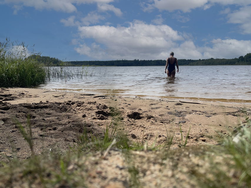 Kvinna i blå baddräkt går ner i vatten.