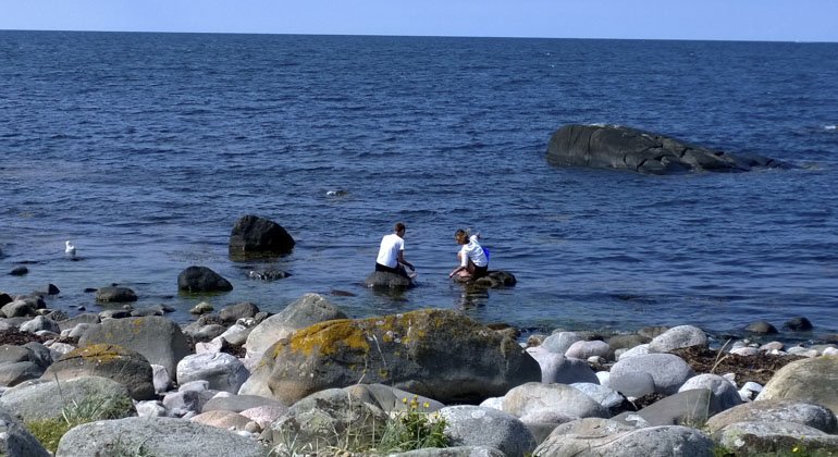 Två personer som sitter på stenar i vattnet