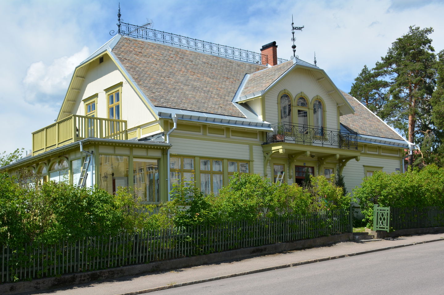 Vacker sekelskiftesvilla från 1902 med ljusgrön fasad och mörkröd dörr