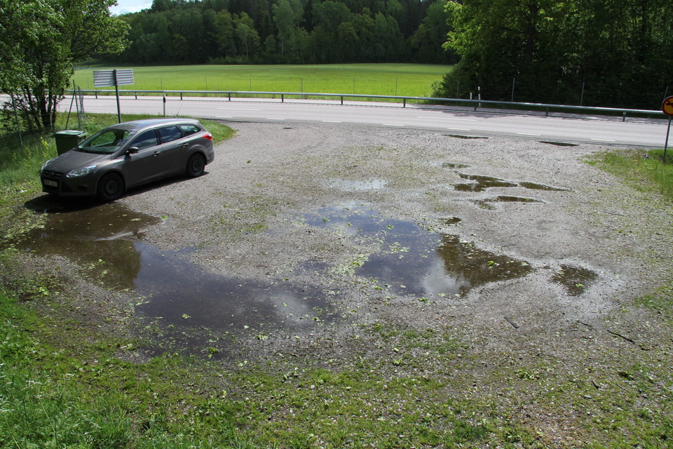 Bil parkerad på parkeringsplats. E20 skymtar i bakgrunden.