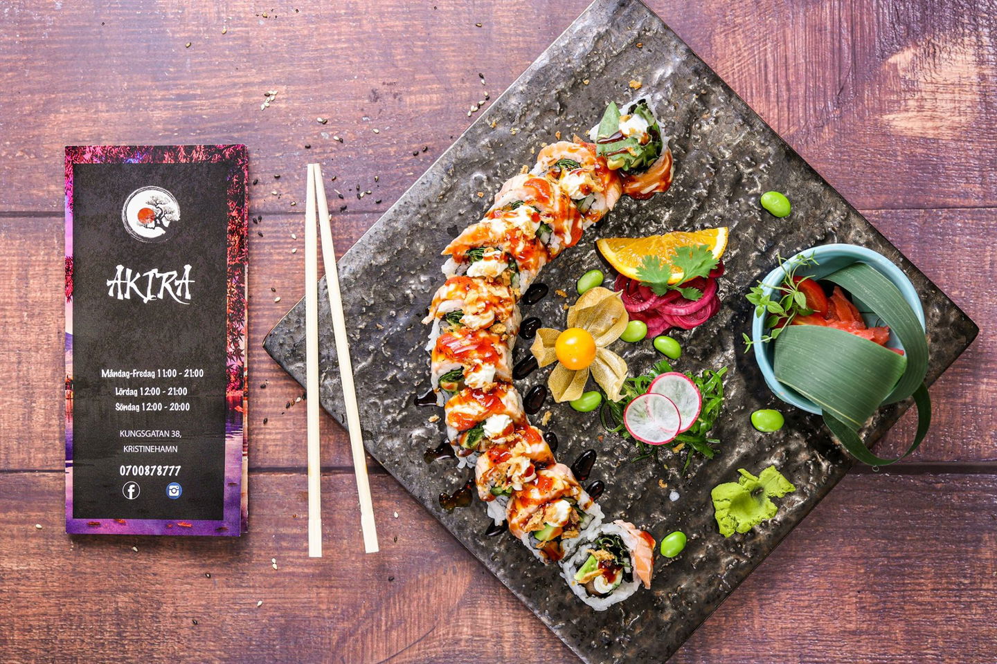 Sushi upplagt på en skiffer platta med en meny vid sidan av.