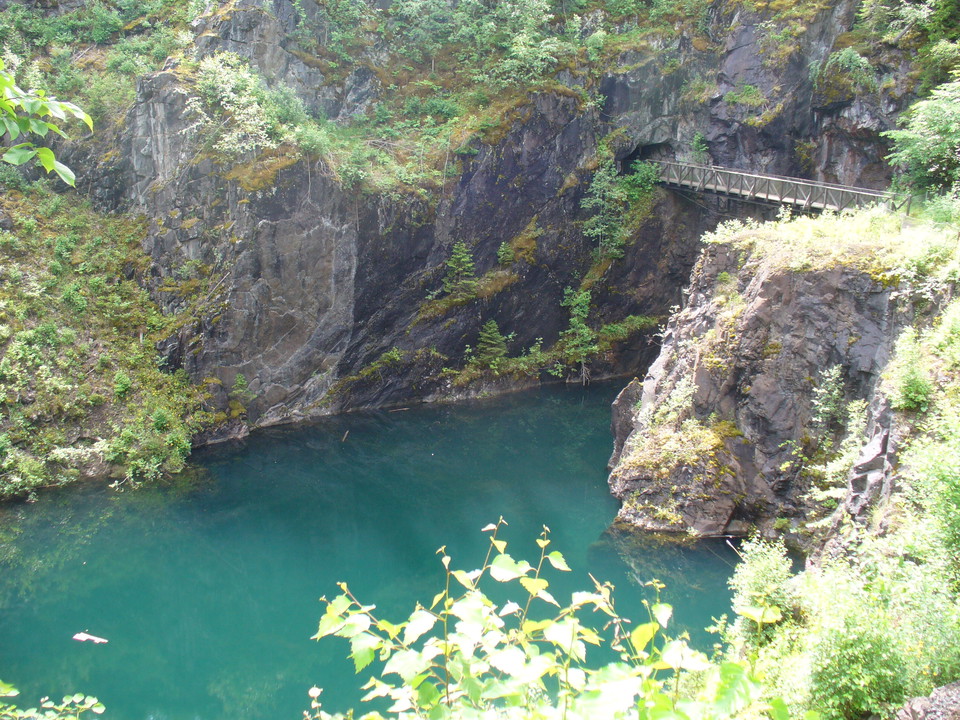Dagbrott med turkosfärgat vatten och en bro som leder över.