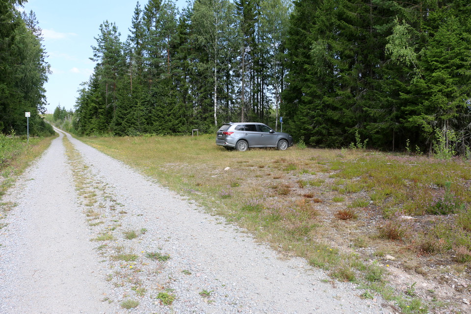 Silverfärgad Suv på en parkeringsyta vid en grusväg.