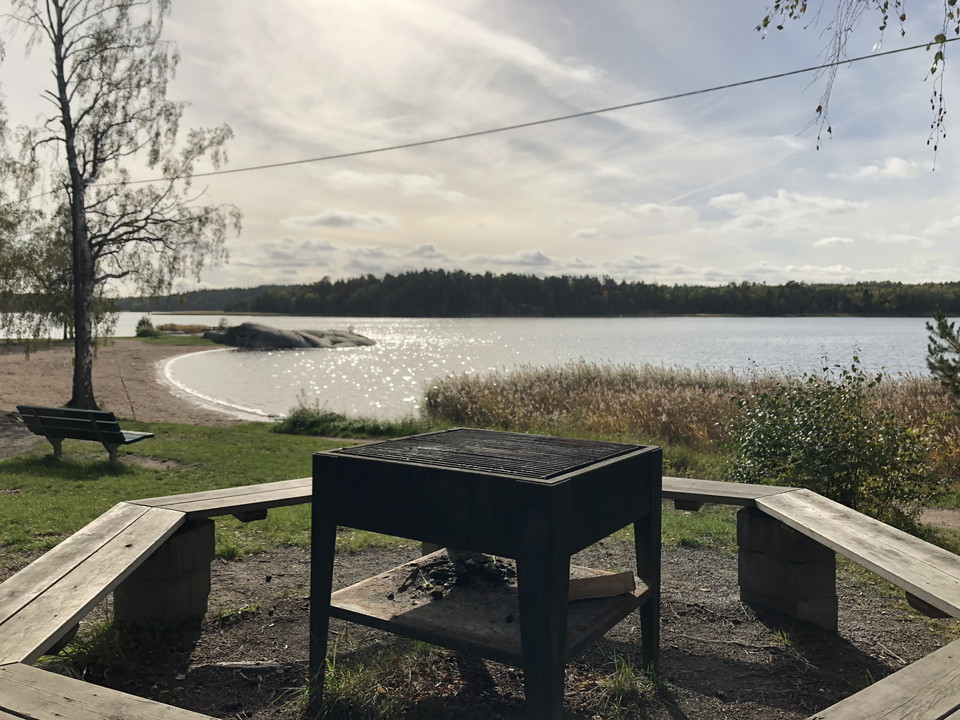 En grillplats med en badstrand i bakgrunden.