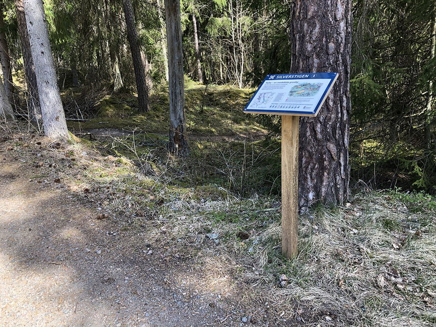 Informationstavla vid grusad stig.