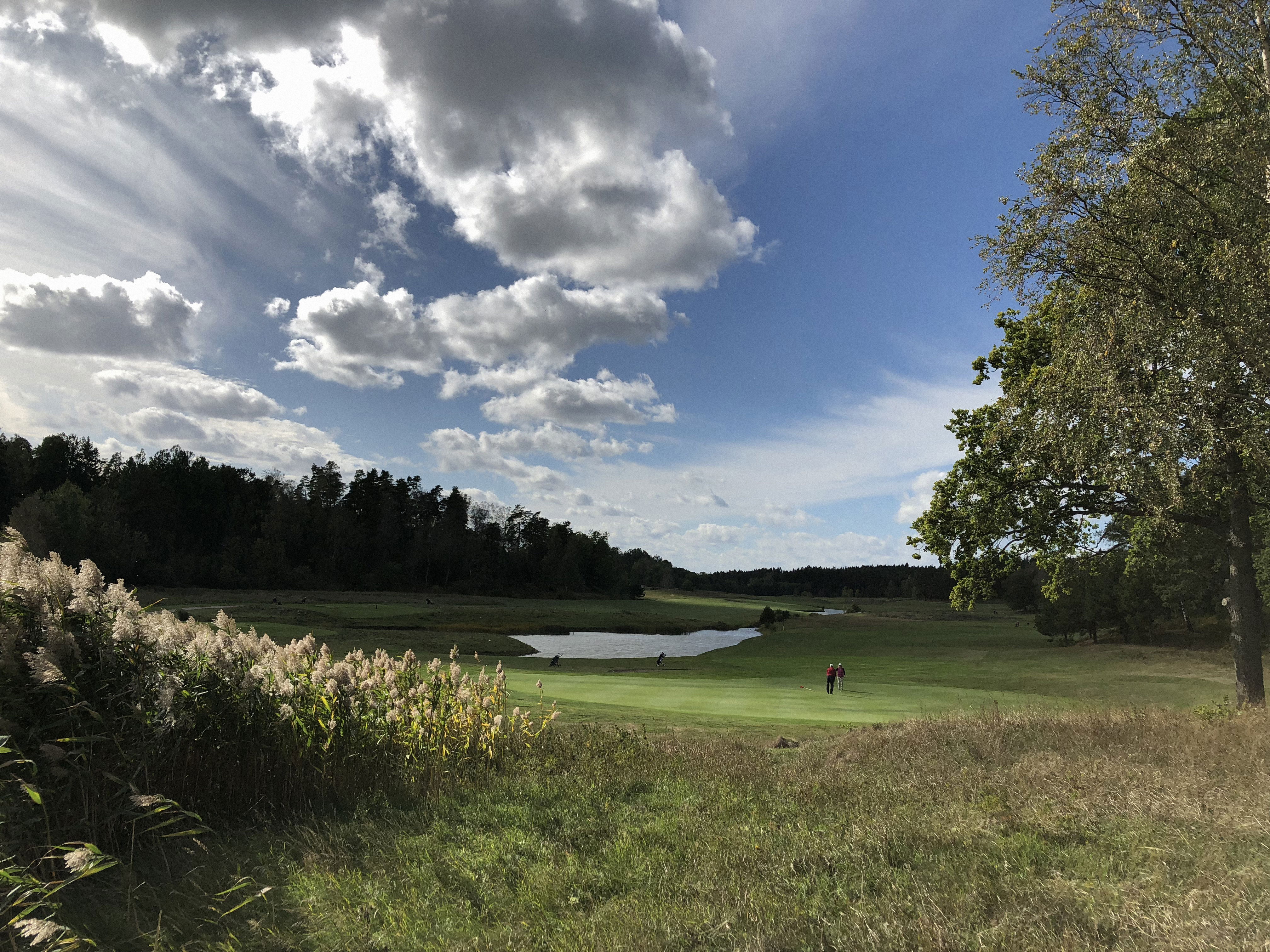 Golfbana med två spelare på greenen.