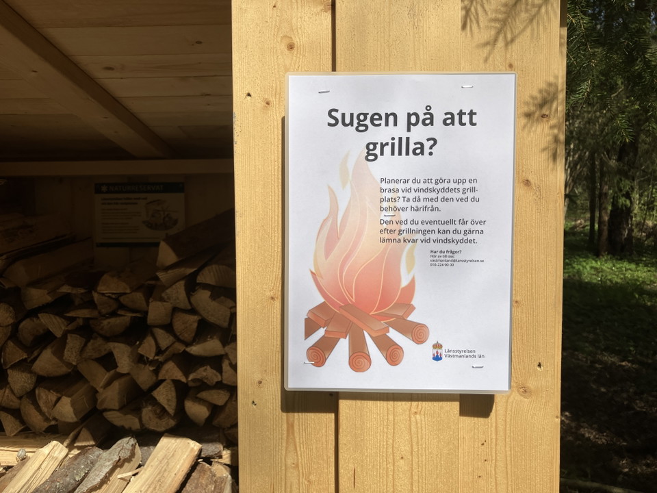 Skylt med information om att ta med ved om man vill grilla vid vindskyddet.