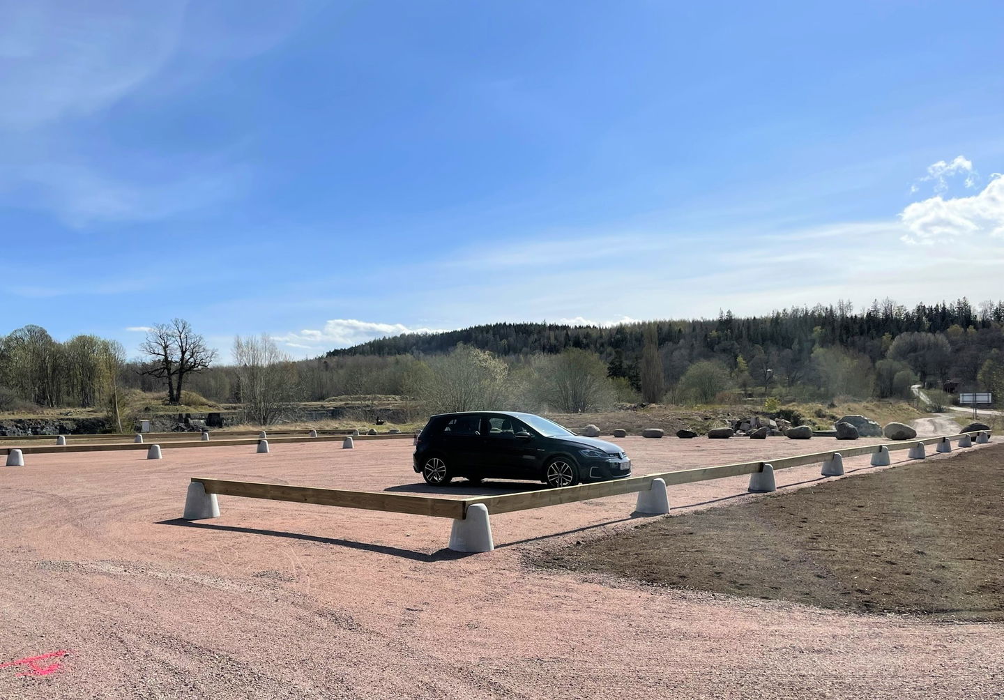 En ensam bil på en i övrigt öde parkeringsplats i Borghamn. I bakgrunden syns Ombergs siluett.