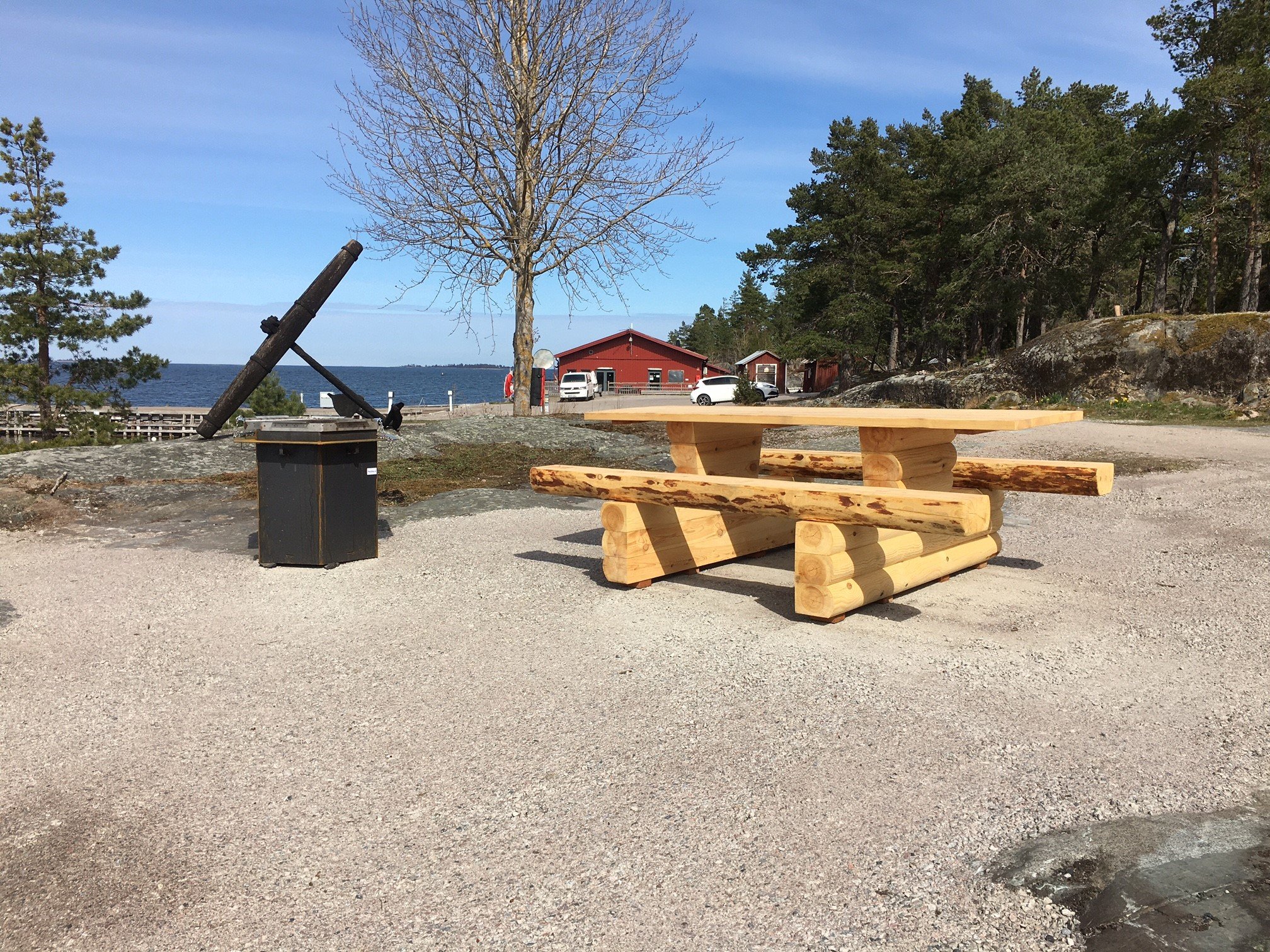 Hårdgjort underlag, grill och tillgänglighetsanpassat fikabord. I bakgrunden Kolhuset och utsikt över havet.