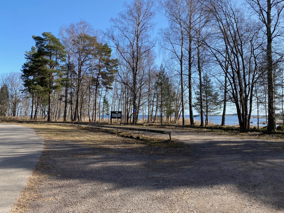 Stor grusad parkering intill vägen med havet i bakgrunden.