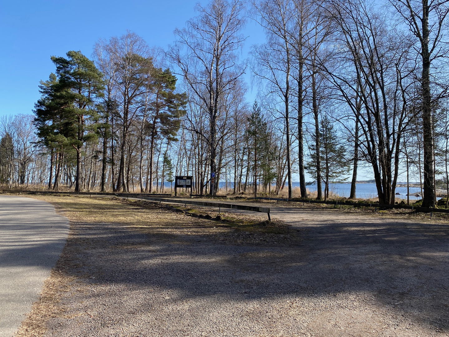 Stor grusad parkering intill vägen med havet i bakgrunden.