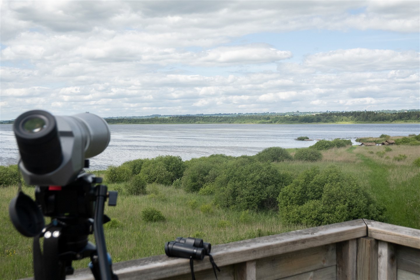 Utsikt över sjö från fågeltorn med kikare suddigt i förgrunden