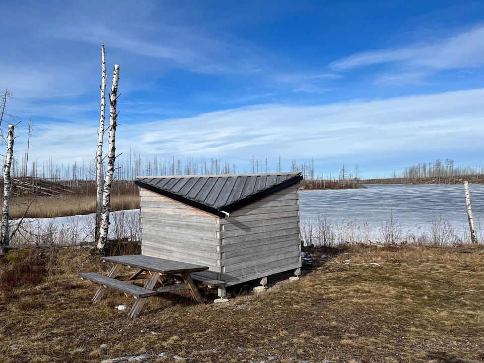 Vindskydd bakifrån, sjö med istäcke.