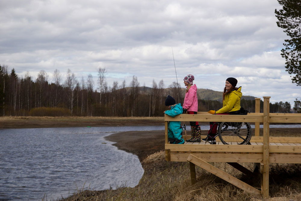 Människor på tillgängliggjord fiskeplats, varav en sittande i rullstol