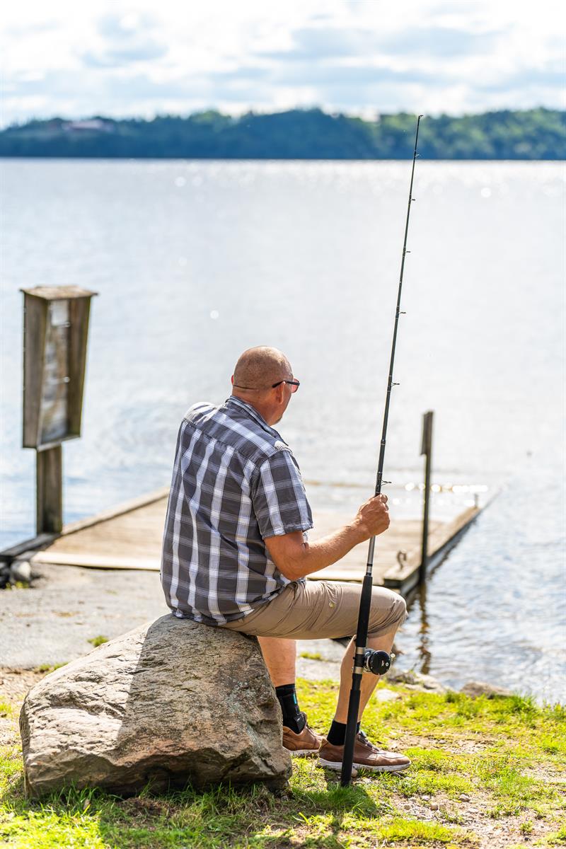 En mann som sitter og fisker ved båtutsettplassen