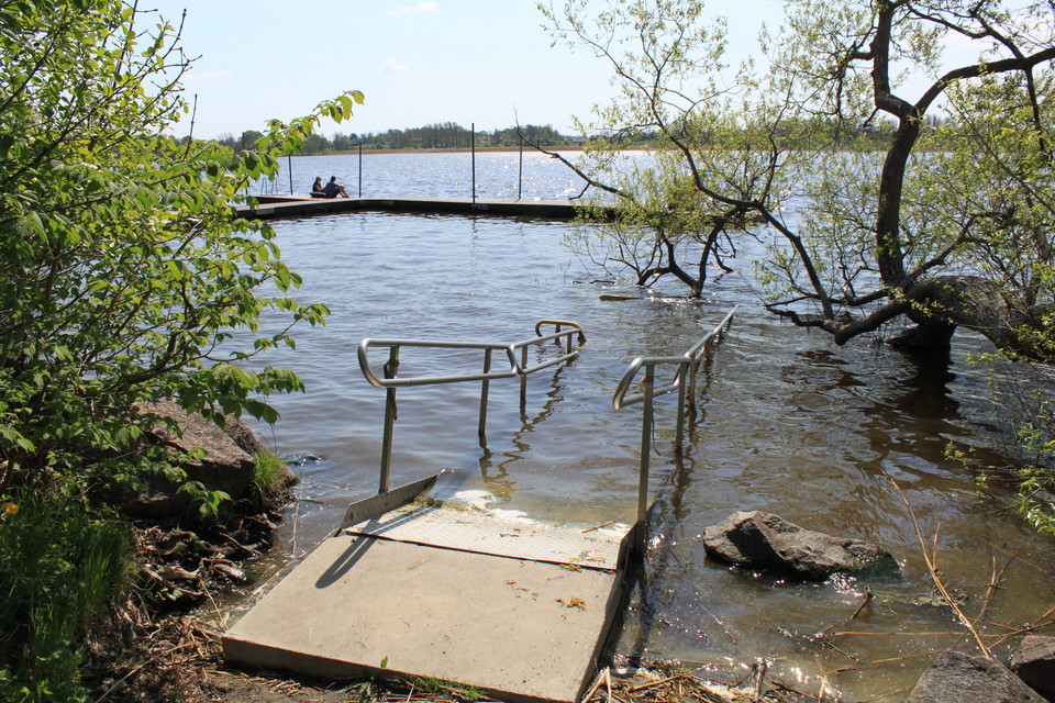 En ramp med handräcken leder ner i vattnet. Framför rampen står en gjuten betongplatta.