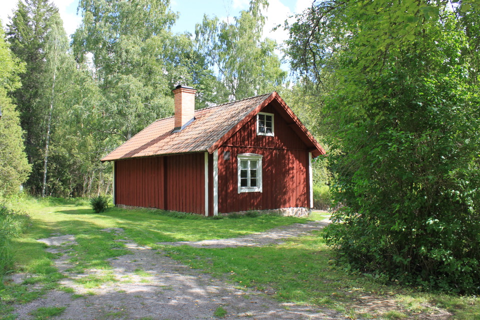 baksida på röd stuga med rött tegeltak