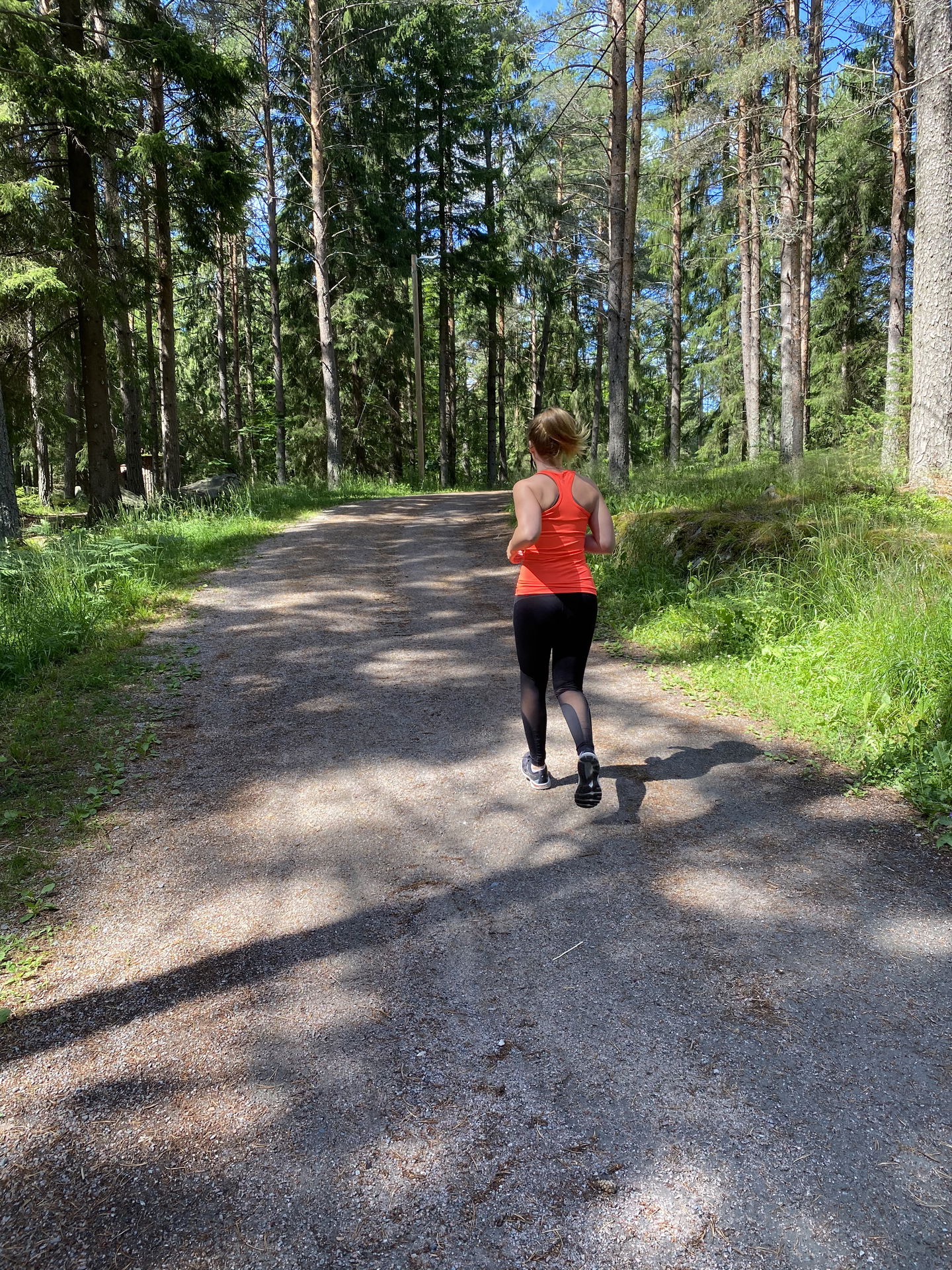 Kvinna springer i motionsspår i skogen