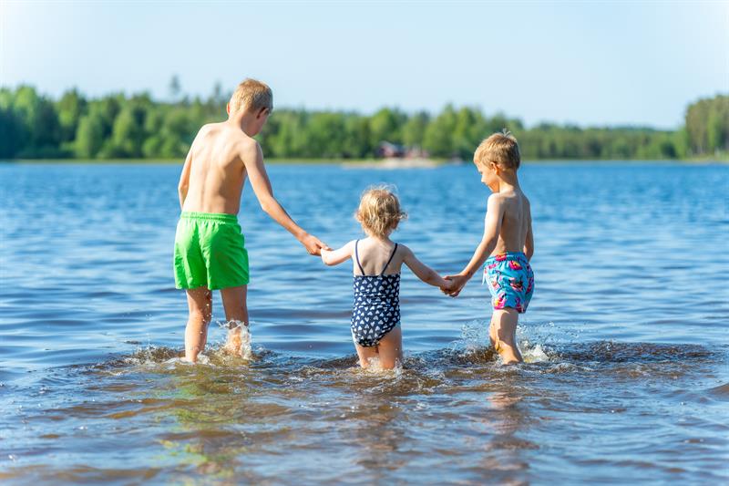 Tre barn på vei ut i vannet for å bade