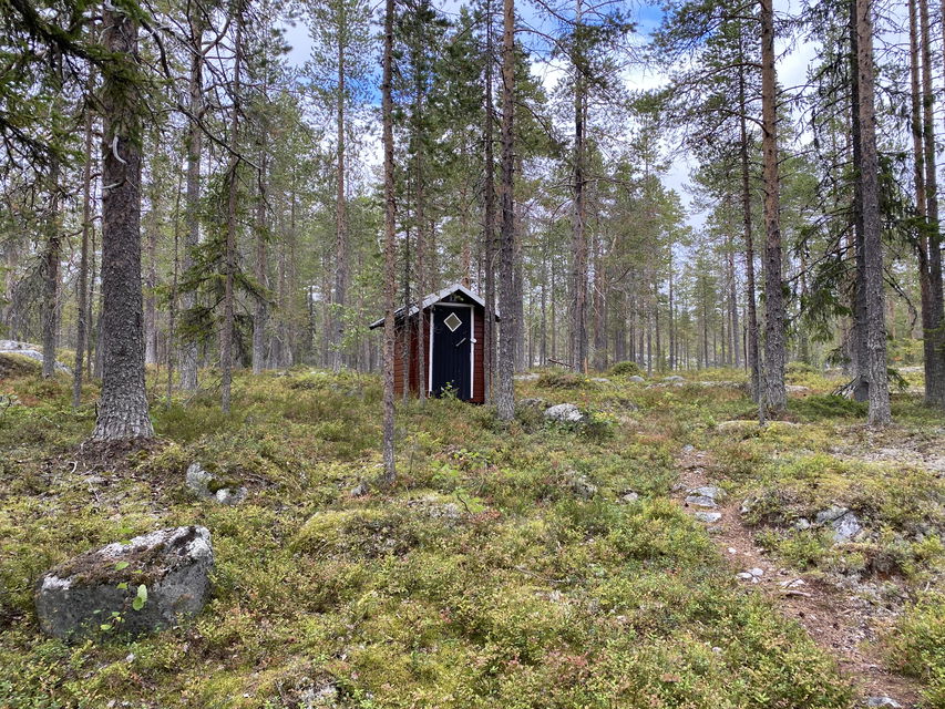 Ett rött litet dass i skogen.
