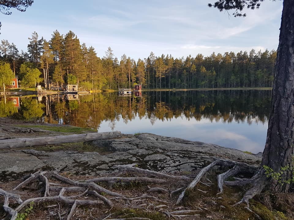 Ottsjön ligger spegelblank, stugor i bakgrunden