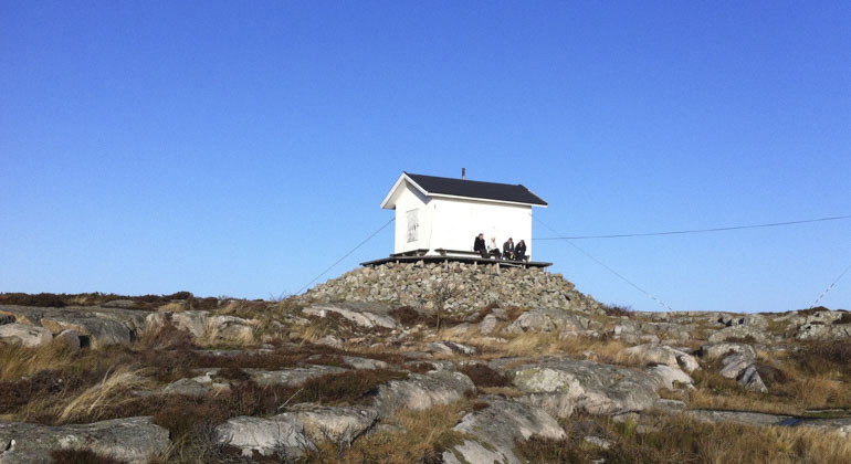 en liten vit stuga på en klippa
