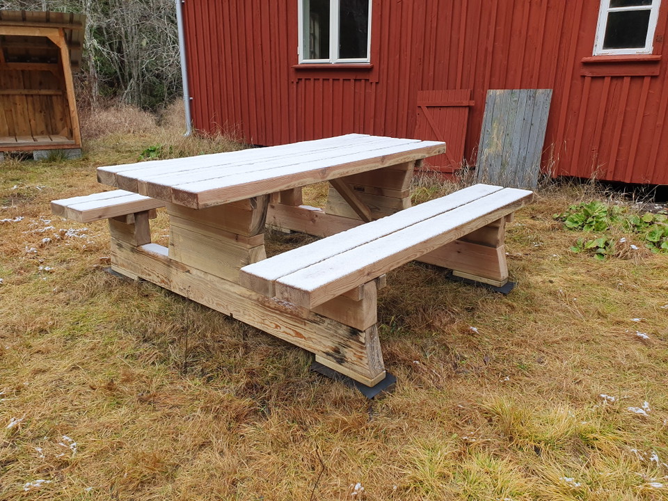 Timrat bänkbord vid stuga.