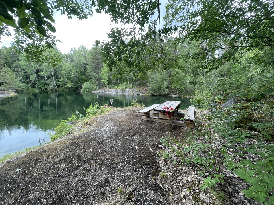 Picknickbord med bänkar och utsikt över ett gammalt stenbrott. På bordet ligger en rod bikini.