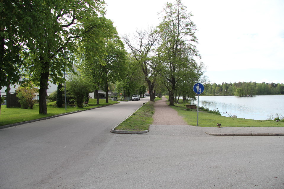 Grusad gångväg bredvid bilväg. Intill gångvägen ligger ån.