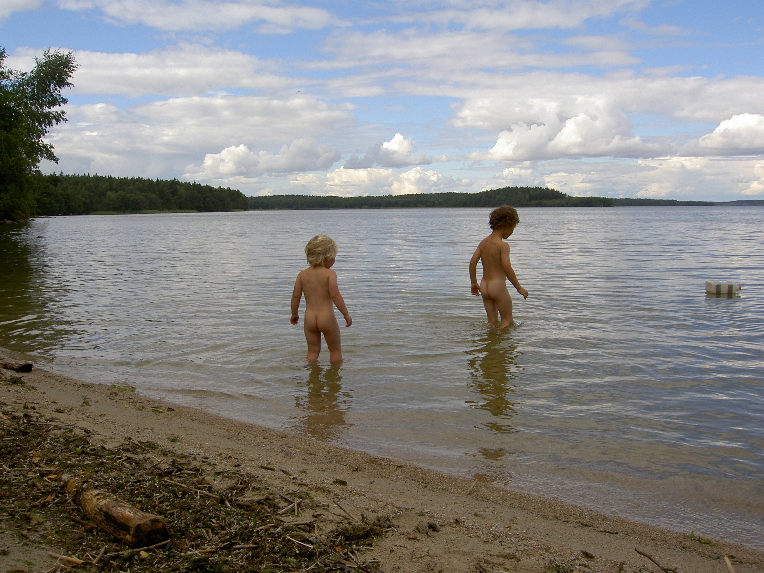 Två små barn går ut i vattnet från en sandstrand