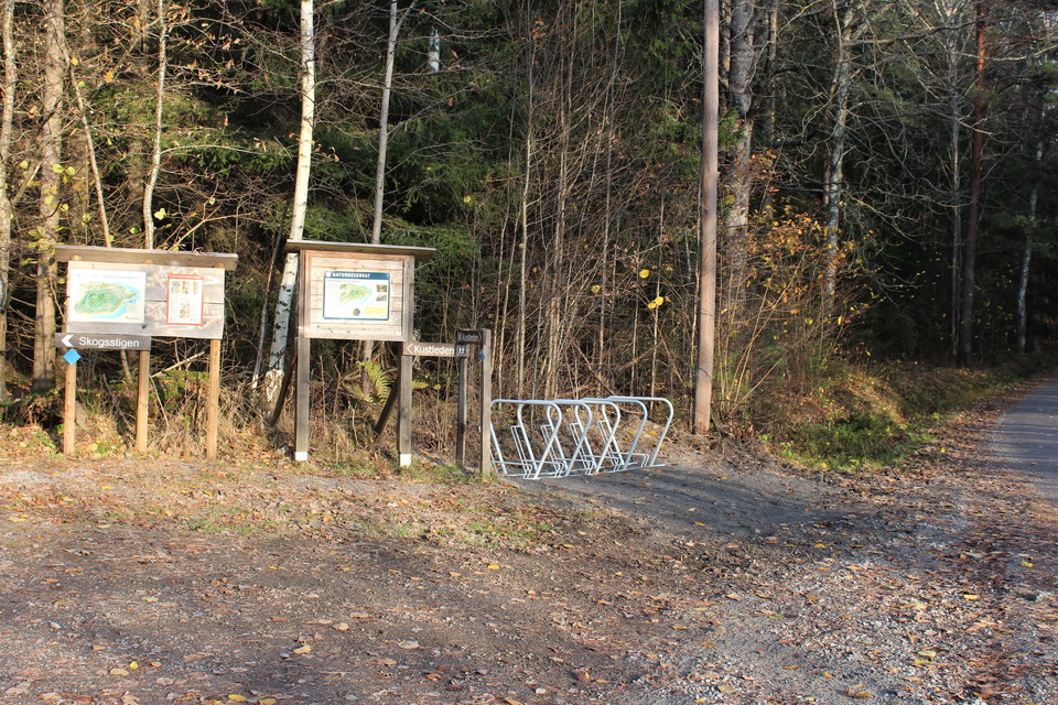 Informationstavlor och cykelställ vid parkeringen.
