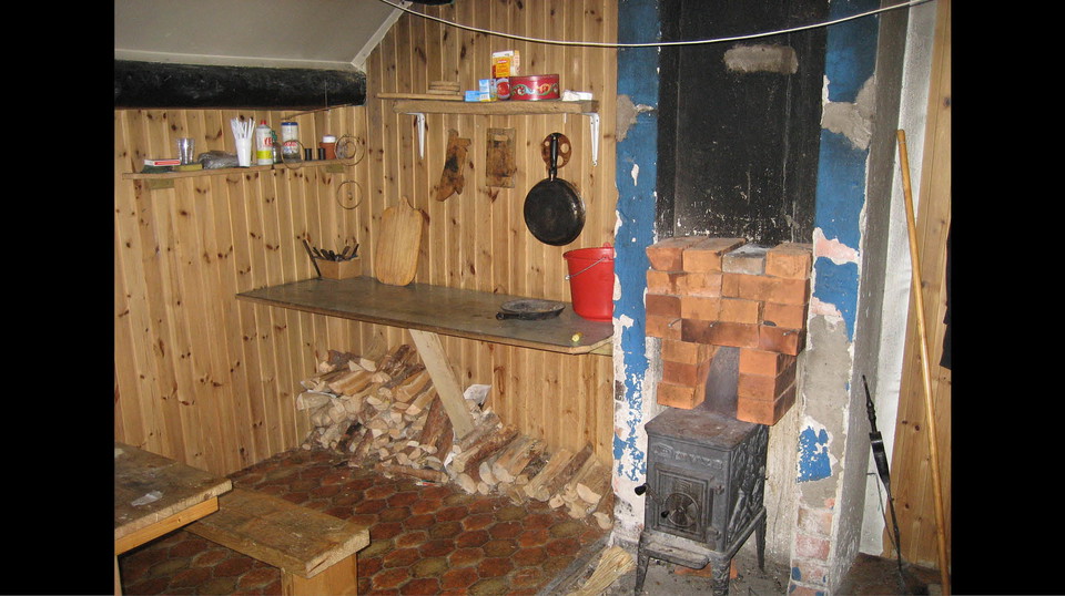 Inne i stugan: arbetsbänk och kamin.