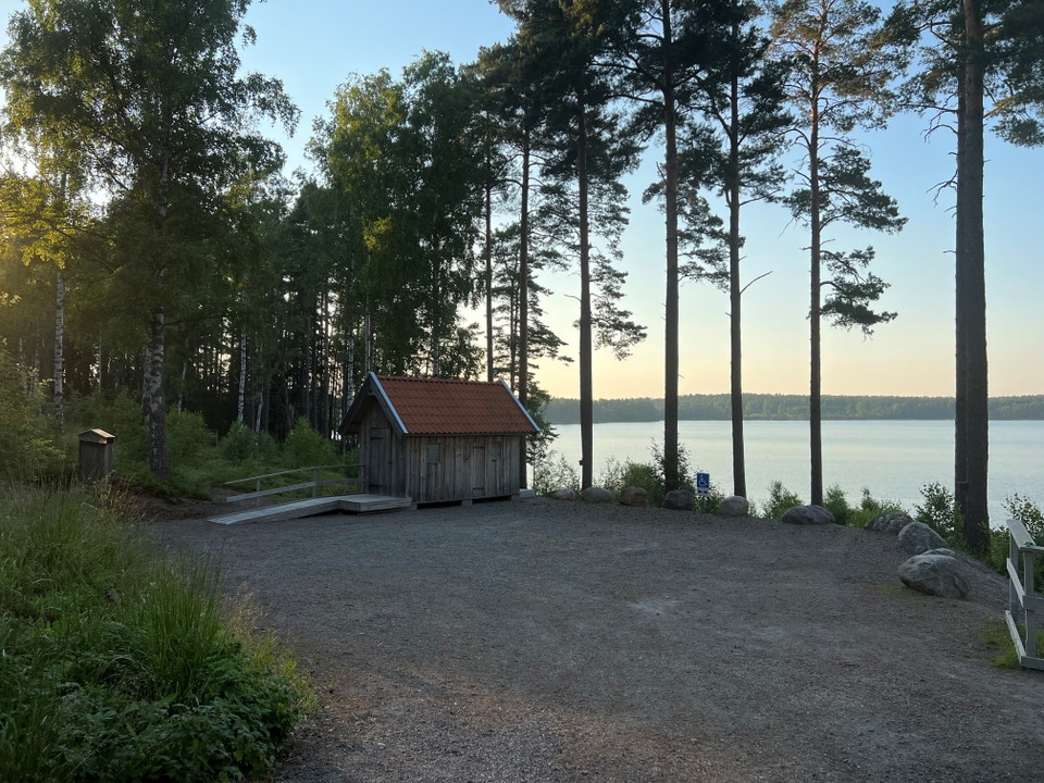 Litet trähus och en grusad parkering.
