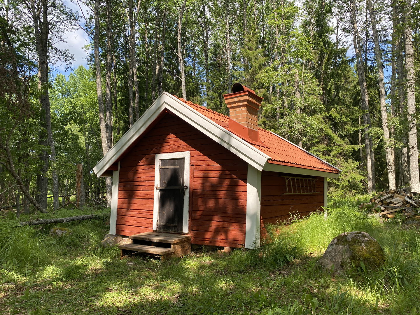 Röd raststuga med vita knutar i skogen