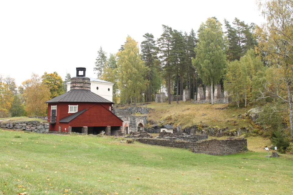 En öppen gräsyta med en byggnad som är omgiven av gammal stenmur.