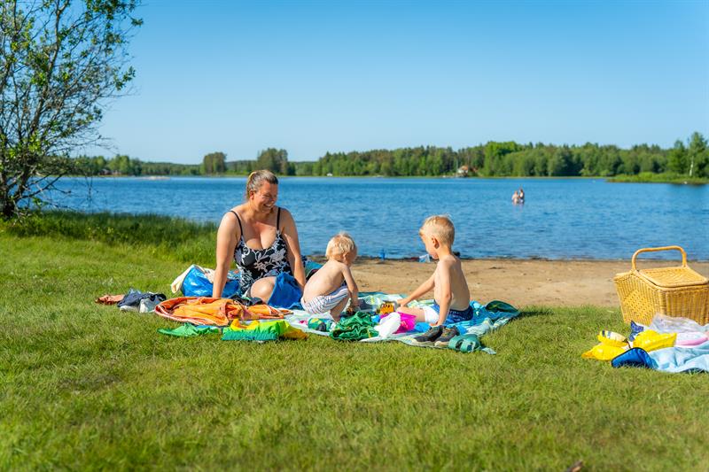 Noen som koser seg på gresset og noen bader i bakgrunnen