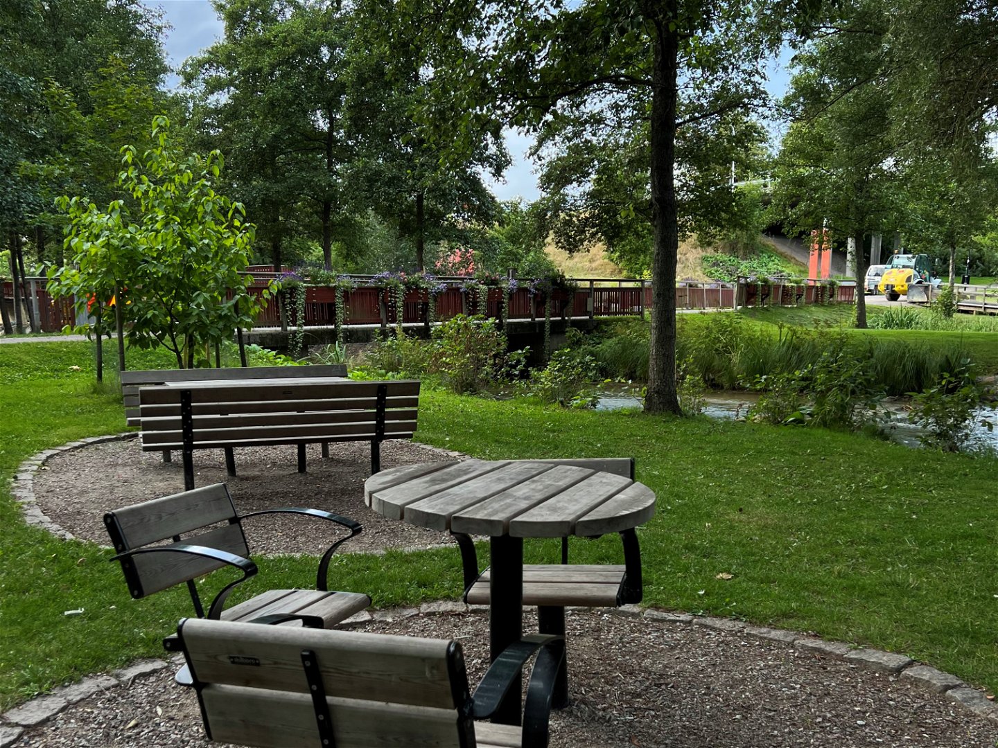 Bord och stolar i trä i en park, intill ett vattendrag