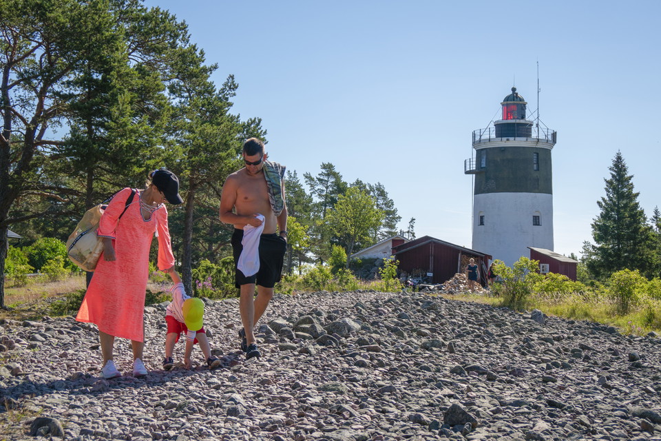 Familj i soligt sommarväder med Storjungfruns fyr i bakgrunden