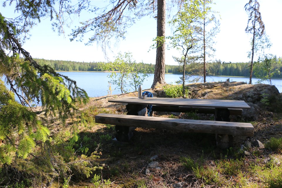 Ett picknickbord på en klippa i skogen, en sjö i bakgrunden.