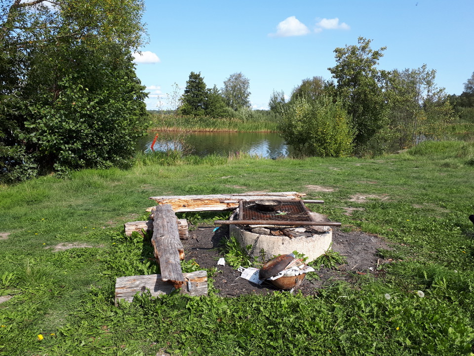 Rund grillplats med två bänkar intill. En blank å i bakgrunden.