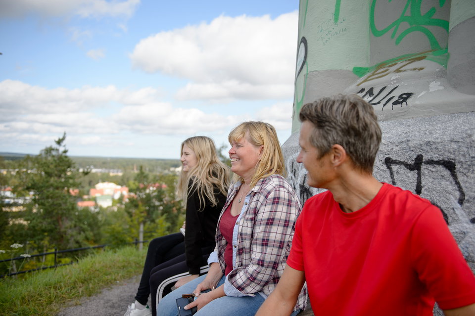 Tre personer sitter på en bänk vid det gröna vattentornet på Västra berget