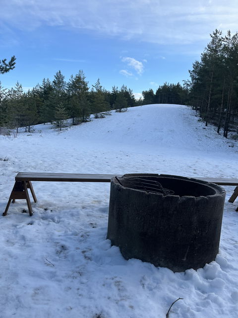 Grill i form av betongrör utanför vindskydd. Vinter