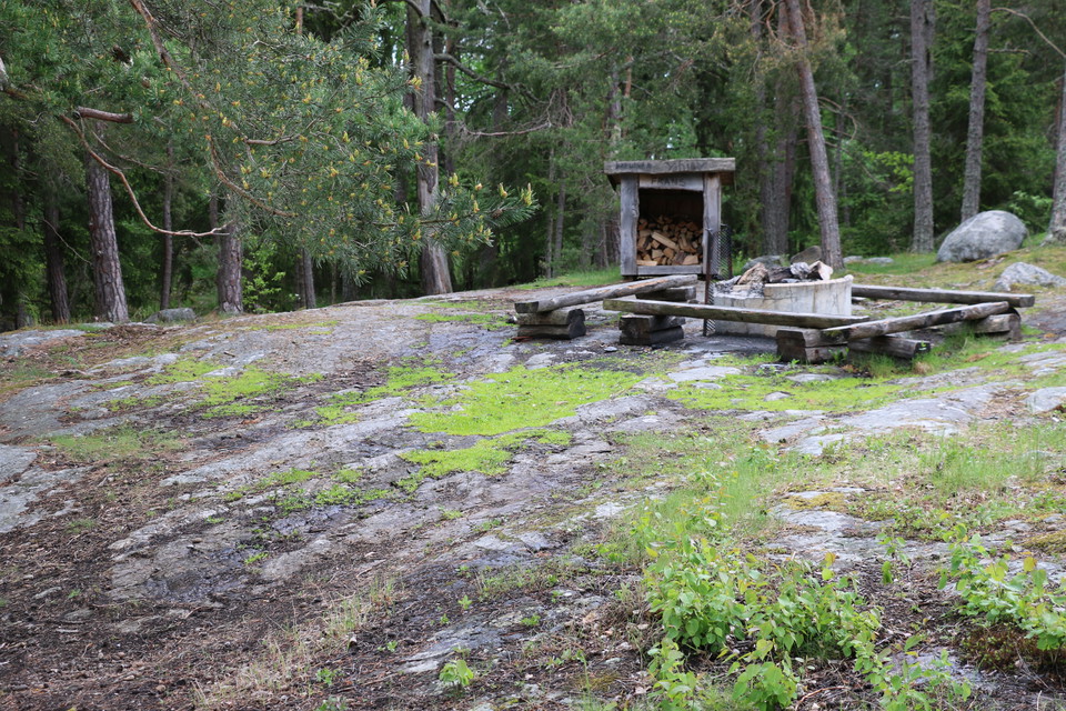 Rastplats på klippor med eldstad, vedförråd och bänkar.