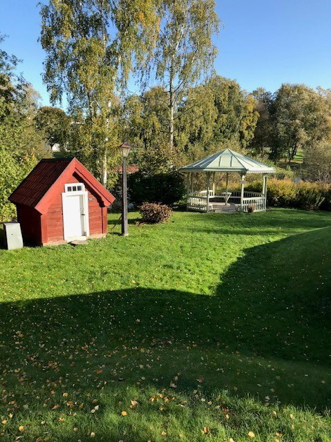 Grönyta och litet rött hus samt lusthus, alla på hembygdsområdet i Mjölby