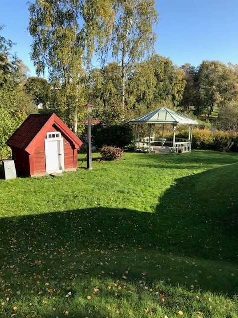 Grönyta och litet rött hus samt lusthus, alla på hembygdsområdet i Mjölby