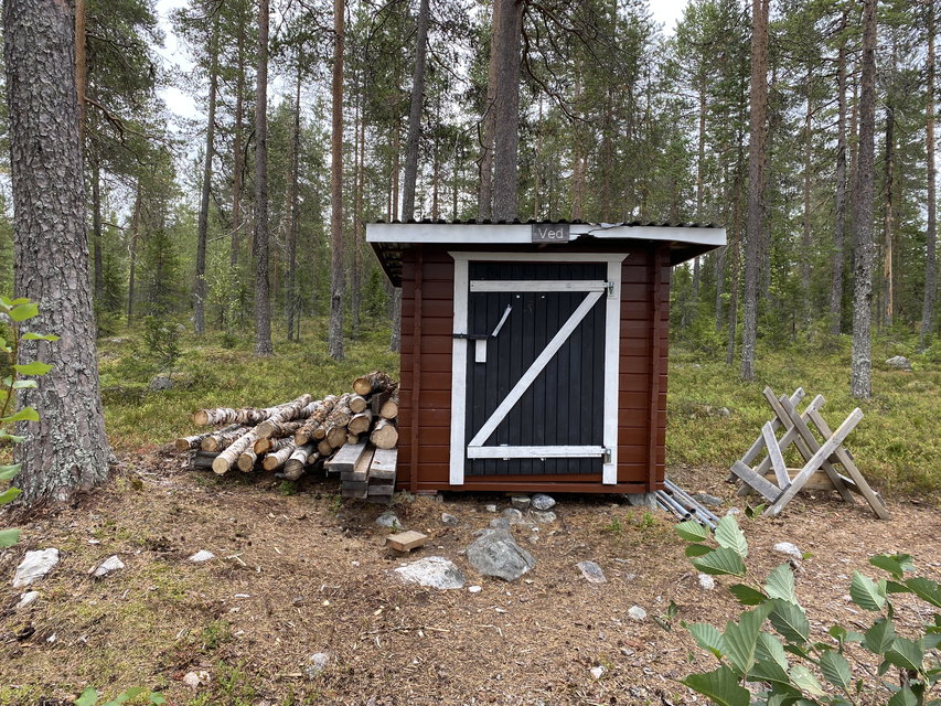 En vedbod omgiven av barrskog.
