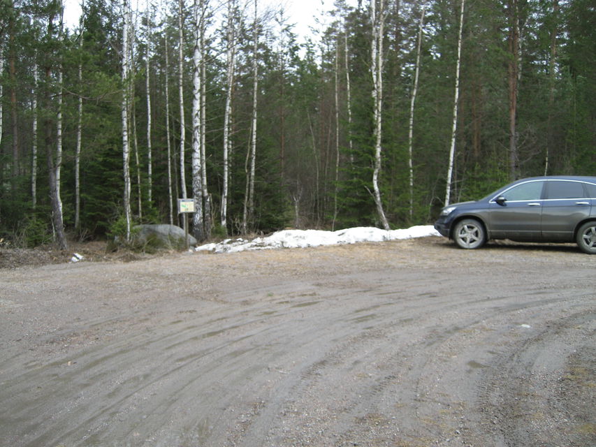 Del av vändplan. En bil står parkerad med fronten mot skogen. Gott om plats för fler bilar.
