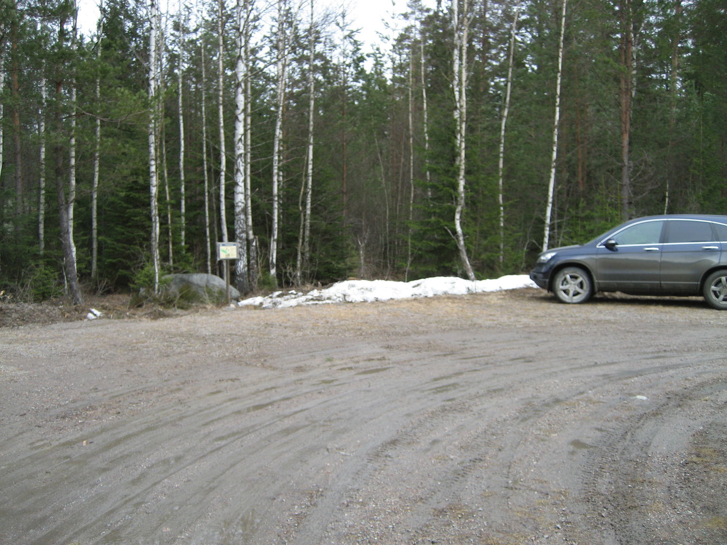 Del av vändplan. En bil står parkerad med fronten mot skogen. Gott om plats för fler bilar.