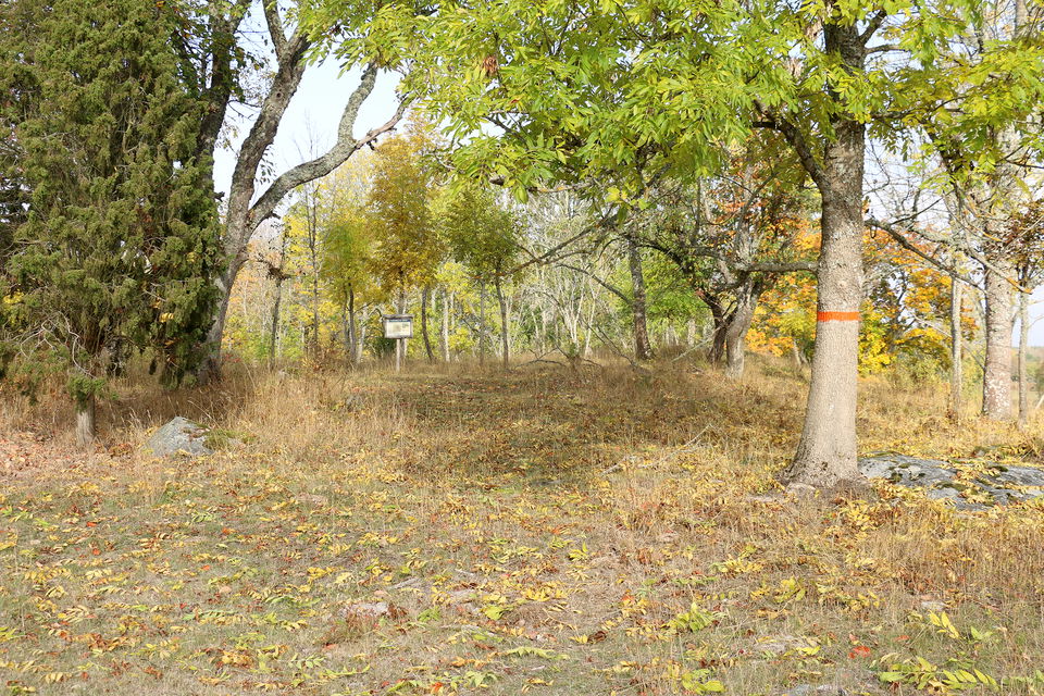 Informationstavla på en träställning på en höjd bland ekar och enar..