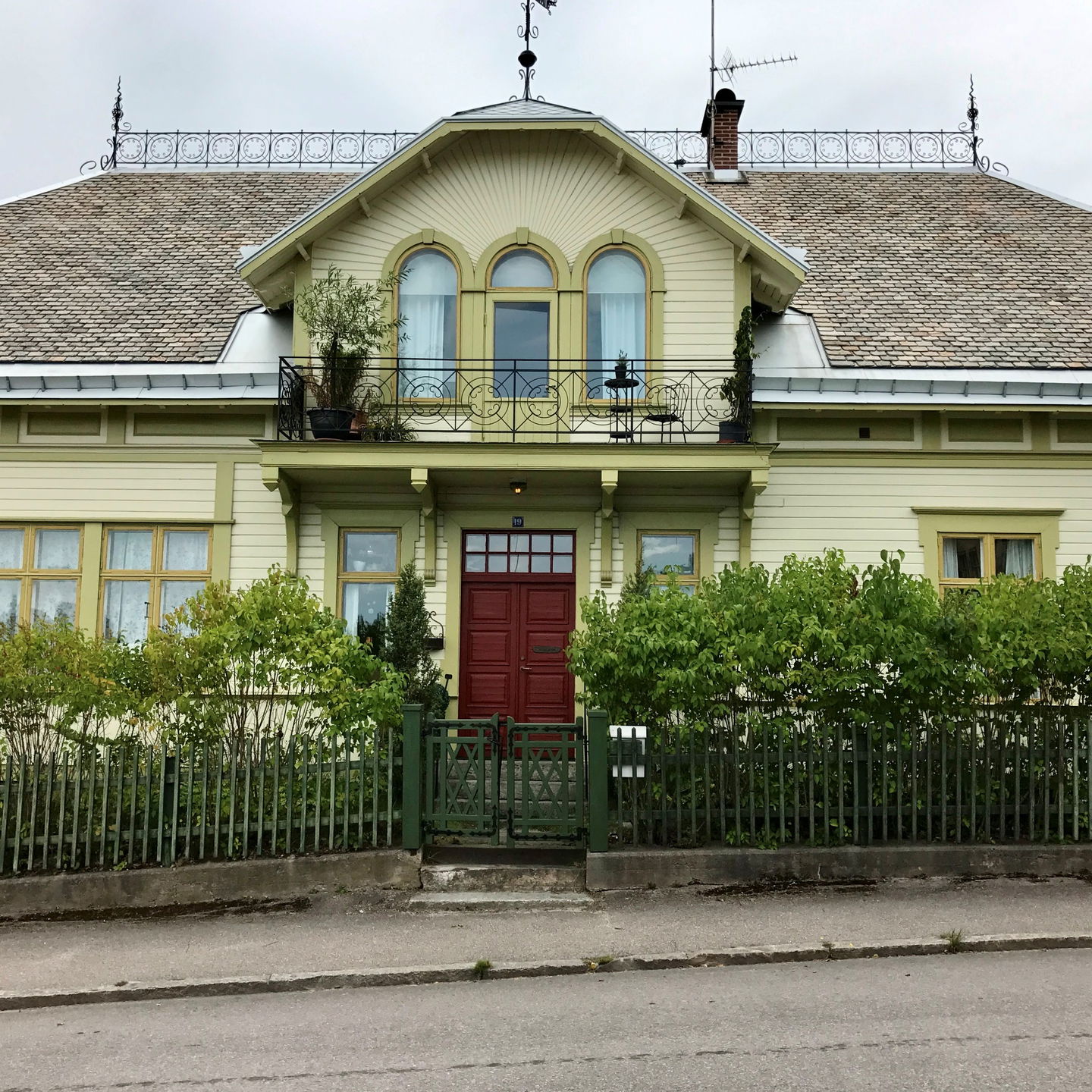Vacker sekelskiftesvilla från 1902 med ljusgrön fasad och mörkröd dörr
